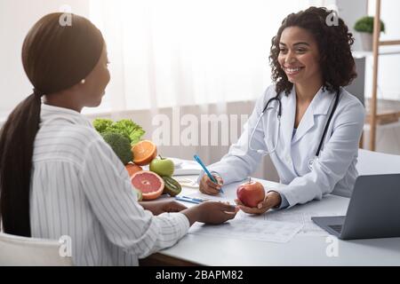 Fröhlicher Ernährungsberater, der den Patienten über eine gesunde Ernährung beraten kann Stockfoto