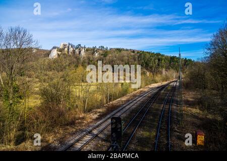 Deutschland, Schienen, die durch die schöne unberührte Naturlandschaft des felsigen schwäbischen juras in blaubeuren führen, mit Blick auf die uralten Burgruinen Hohengerh Stockfoto