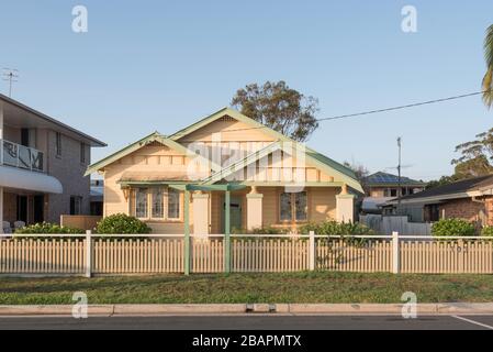 Zwischen zwei modernen Häusern am Marine Drive in Tea Gardens liegt dieser Federation Weatherboard Bungalow mit seinen wunderschönen Bleilichtfenstern. Stockfoto