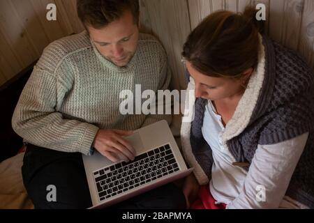 Junges Paar, das einen Laptop verwendet, im Bett, das eine Bestellung während der Quarantäne macht. Internet, Technologie, Familie, Liebe, Beziehungskonzept gedreht. Stockfoto
