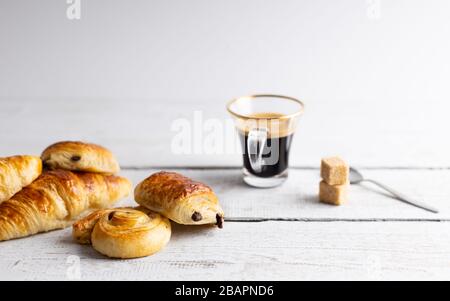 Frühstück mit Croissants, Zimtbrötchen und Schokoladeplätzchen, frischem Orangensaft und Kaffee auf der Seite auf weißem Hintergrund. Stockfoto