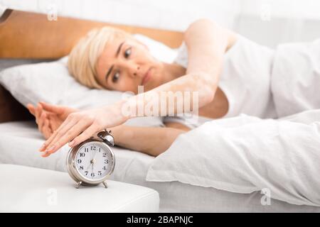 Frau, die aufwacht und den Wecker ausschaltet Stockfoto
