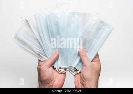 Männlicher Patient, der die medizinische Gesichtsmaske von Lot in den Händen auf weißem Hintergrund hält. Concept Coronavirus Quarantäne, Grippe, Luftgetragene Krankheiten, Pandemie-Ausbruch. Stockfoto