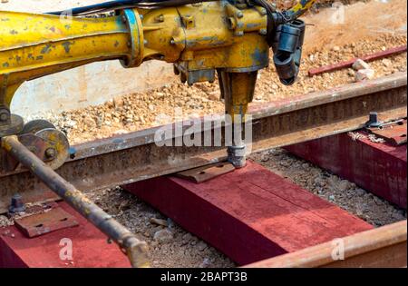 Bahnarbeiter, die die Gleisschiene verschrauben. Detailarbeiter mit mechanischem Schraubenschlüssel Stockfoto