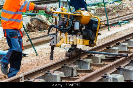 Bahnarbeiter, die die Gleisschiene verschrauben. Detailarbeiter mit mechanischem Schraubenschlüssel Stockfoto