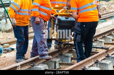 Bahnarbeiter, die die Gleisschiene verschrauben. Detailarbeiter mit mechanischem Schraubenschlüssel Stockfoto