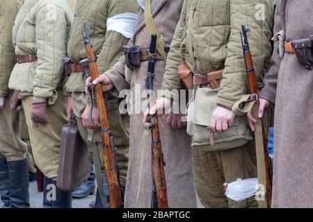 Umbenennende, die als Soldaten der sowjetischen Infanterie des zweiten Weltkriegs verkleidet sind, halten Gewehrwaffen in Händen Stockfoto