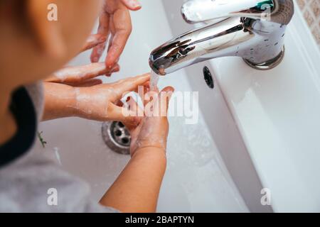 Mutter und Sohn waschen ihre Hände mit Seife und Wasser im Badezimmer. Reinigung der Handhygiene, um den Ausbruch von Coronavirus zu verhindern. Schutz Agai Stockfoto