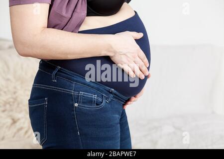 Hose für Schwangere. Spezielles elastisches Band für den Bauch, Frau im Schlafzimmer, Seitenansicht Stockfoto