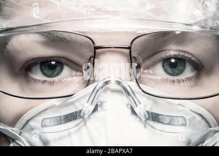 Horizontale extreme Nahaufnahme von nicht erkennbaren kaukasischen Frauen, die Schutzmaske, medizinische Kappe und Brille mit Blick auf die Kamera tragen Stockfoto