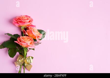Gratulation Eckrahmen Rand von blühendem Blumenstrauß aus frischen Rosen und Gypsophila-Blume auf hellrosa Hintergrund, Kopier Raum. Flaches Lay. Stockfoto