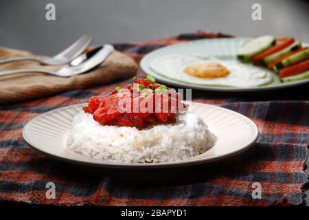 Foto von frisch gekochtem Tocino oder gehärtetem Schweinefleisch, serviert mit gebratenem Reis und Ei mit Gemüse. Stockfoto