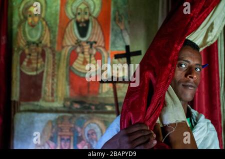 Debre Sina Beta Maryam Kirche, Lake Tana, Bahir dar, Äthiopien. Ein Priester posiert majestätisch mit seinem Kreuz an der Tür des Klosters Birgida Maryam auf o Stockfoto