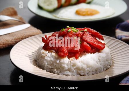 Foto von frisch gekochtem Tocino oder gehärtetem Schweinefleisch, serviert mit gebratenem Reis und Ei mit Gemüse. Stockfoto