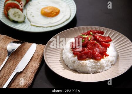 Foto von frisch gekochtem Tocino oder gehärtetem Schweinefleisch, serviert mit gebratenem Reis und Ei mit Gemüse. Stockfoto