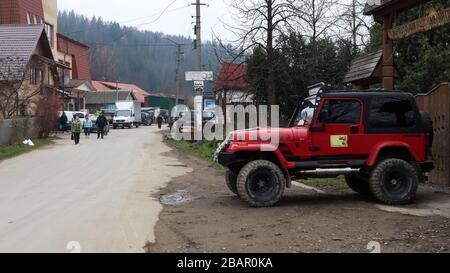 Ukraine, Yaremche - 20. November 2019: Ein rotes Geländewagen Jeep Wrangler 4.0i V6 wird auf einer Landstraße in der Nähe eines Hauses in einer kleinen Stadt ukrainischer Karpaten geparkt Stockfoto