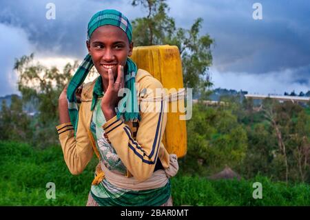 Ein Mädchen führt eine Dose Wasser über ein Feld in Lalibela, Amhara-Region, Nordäthiopien Stockfoto