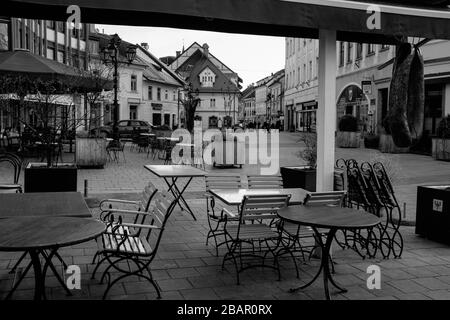 Kranj, Slowenien, 20. März 2020: Leere Tische mit geschlossenen Bars und Restaurants in der Altstadt von Kranj, Slowenien, während des Coronavirus-Ausbruchs landesweit gesperrt. Stockfoto