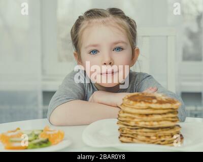 Kleines hübsches Mädchen, das Frühstück isst, drinnen Stockfoto