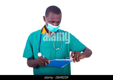 Gutaussehender junger männlicher Arzt, der eine medizinische Maske trägt und im Krankenhaus Notizen in die Zwischenablage schreibt. Stockfoto