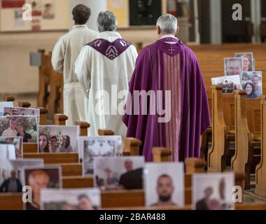 Achern, Deutschland. März 2020. Pfarrer Joachim Giesler (h) geht mit Gemeindemitgliedern in der Pfarrkirche an Fotos vorbei. Gottesdienste finden wegen des Coronavirus vor leeren Kirchen statt. Die Pfarrei hatte ihre Gemeindemitglieder gebeten, Bilder zu senden. Mehr als 300 Bilder wurden ausgedruckt und an den Kirchenbänken aufgehängt. Credit: Patrick Seeger / dpa / Alamy Live News Stockfoto