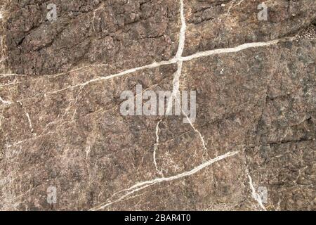 Nahaufnahme der grauen Felsoberfläche am Meer mit weißen Adern Stockfoto