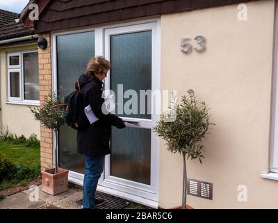 Willingham, Cambridgeshire, Großbritannien. März 2020. Ein Freiwilliger liefert Flugblätter zu den Häusern im Dorf, in denen er die lokale Unterstützung erklärt, die für die Menschen in der Coronavirus Pandemie zur Verfügung steht. Der Willingham Hub wurde von örtlichen Freiwilligen eingerichtet, die Menschen beim Ausbruch des Covid-19-Virus unterstützen sollen. Kredit: Julian Eales/Alamy Live News Stockfoto