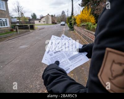 Willingham, Cambridgeshire, Großbritannien. März 2020. Ein Freiwilliger liefert Flugblätter zu den Häusern im Dorf, in denen er die lokale Unterstützung erklärt, die für die Menschen in der Coronavirus Pandemie zur Verfügung steht. Der Willingham Hub wurde von örtlichen Freiwilligen eingerichtet, die Menschen beim Ausbruch des Covid-19-Virus unterstützen sollen. Kredit: Julian Eales/Alamy Live News Stockfoto