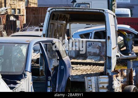 Alter grauer Wagenrahmen zerlegte Wagen mit rostigen Teilen auf der Straße in der Nähe des Zauns. Stockfoto