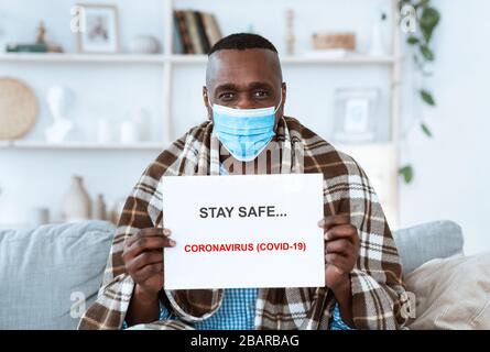 Bleiben Sie bei einem Virusausbruch sicher. Ein erfahrener afroamerikanischer Mann hält Papier mit Anti-Coronavirus-Text in Innenräumen Stockfoto