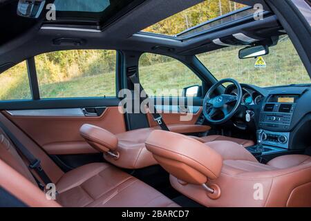 Mercedes Benz W204-Innenraum mit Vorder- und Rücksitzen, Fahrer und Beifahrer, Teil vom Lenkrad, Vorhang hinten, braunes Leder, Stockfoto