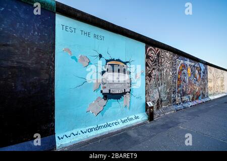 Berlin, Deutschland. März 2020. 26.03.2020, das Denkmal der East Side Gallery auf dem längsten noch erhaltenen Abschnitt der Berliner Mauer in der Muhlenstraße zwischen Berlin Ostbahnhof und Oberbaumbrücke entlang der Spree in Berlin-Friedrichshain. Sie präsentiert eine ständige Freilichtgalerie mit Werken verschiedener Künstler. Hier ist das Werk "DEN REST testen" der Künstlerin Birgit Kinder, das einen durch Sie durch die Wand kommenden Trabant zeigt. --- nur für redaktionelle Zwecke! --- nur für redaktionelle Zwecke! --- weltweite Nutzung Credit: Dpa / Alamy Live News Stockfoto