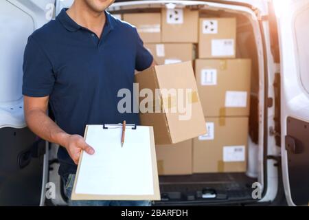 Lächelnder Liefermann mit seinem Lieferwagen Stockfoto