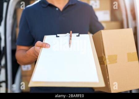 Lächelnder Liefermann mit seinem Lieferwagen Stockfoto