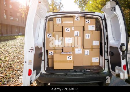 Lächelnder Liefermann mit seinem Lieferwagen Stockfoto