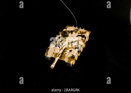 Spielzeug eines Panzers mit Armee-Mustern auf einem schwarzen Oberfläche Stockfoto