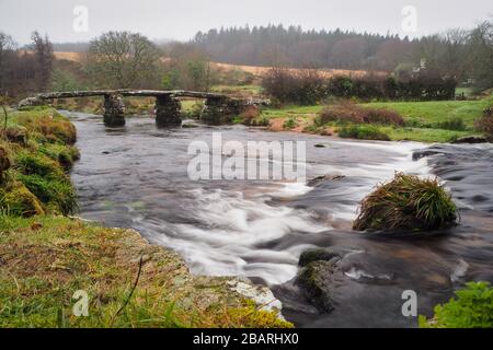 Steinklapperbrücke aus dem 13. Jahrhundert über den East Dart River bei Postbridge, Dartmoor-Nationalpark, Devon, Großbritannien Stockfoto