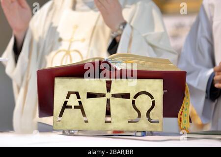 Roman Missale auf dem Altar und Priester feiern im Hintergrund die Messe Stockfoto