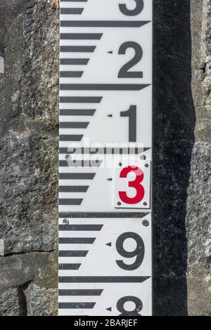 Flusswasserspiegel Messlehre an der abschüssigen Sperrmauer am River Fowey bei Lostwithiel. Metapher: Steigender Wasserstand, Hochwasserschutz. Stockfoto