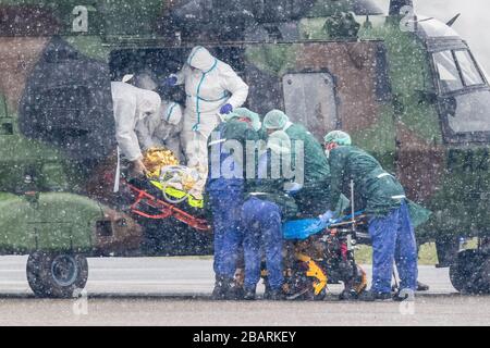 29. März 2020, Nordrhein-Westfalen, Mülheim an der Ruhrgebiet: Ein Patient wird am Flughafen von einem Militärhubschrauber zu einem Rettungswagen transportiert. Insgesamt sollen zwei Patienten von der französischen Metz-Klinik ins Essener Universitätsklinikum gebracht werden. Foto: Marcel Kusch / dpa Stockfoto