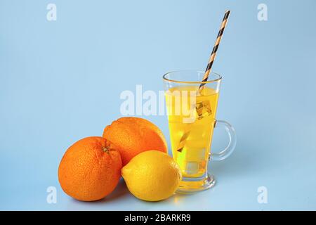 Frischer Multifruchtsaft mit Eis aus Glas. Orange und Zitrone auf blauem Grund Stockfoto