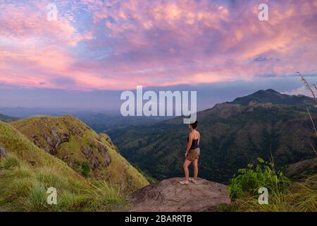 Mädchen, das auf dem Gipfel des Little Adam's Peak bei Sonnenuntergang in Ella, Sri Lanka steht Stockfoto