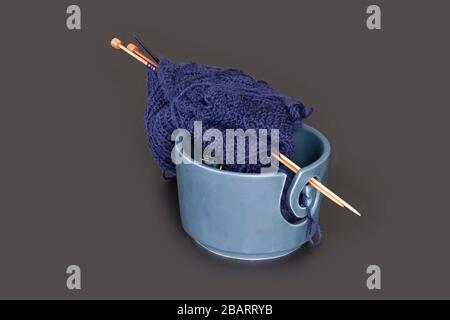 Knitting tools, ball of wool yarn for knitting and wooden needles. Blue yarns in a bowl isolated on dark gray background table. Still life with copy s Stockfoto