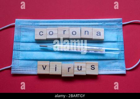 Schutzmaske für chirurgische Eingriffe mit CORONAVIRUS-TEXT. Roter Hintergrund. Stockfoto
