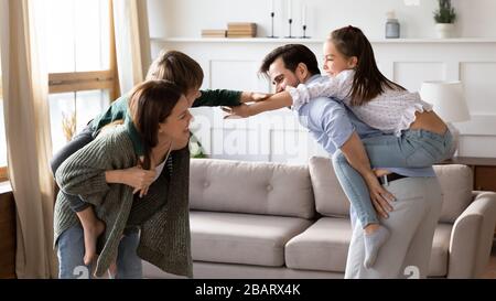 Eltern, die kleine Kinder zurückhalten und Spaß zu Hause haben. Stockfoto