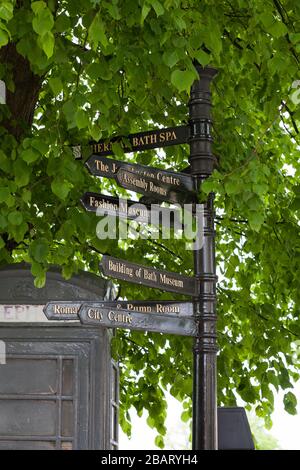 Wegweiser zu Sehenswürdigkeiten in Bath: Fingerschilder, teilweise von Blättern bedeckt, die Touristen zu den vielen Attraktionen in der Stadt Bath führen. Stockfoto