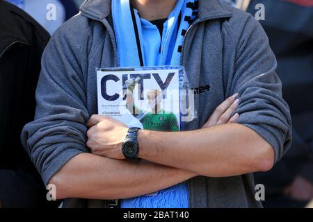 Ein Fan von Manchester City hält das Spieltagsprogramm vor dem Anpfiff ab Stockfoto