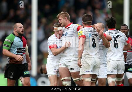 Saracens Spieler feiern nach dem Abpfiff, während Harlequins Spieler niedergeschlagen bleiben Stockfoto