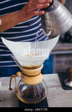 Männliche barista über eine Kaffeemaschine eine schöne Tasse Kaffee zu machen. Cafe Arbeiter Vorbereitung einen Kaffee Stockfoto