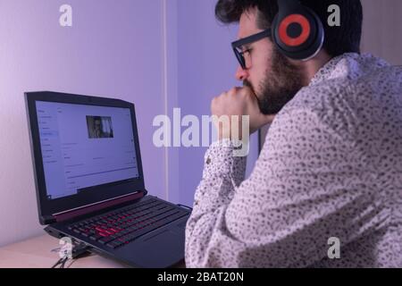 Der junge Mann hört den Anruf mit dem Kopfhörer, um sich besser auf das Argument des Anrufs zu konzentrieren Stockfoto